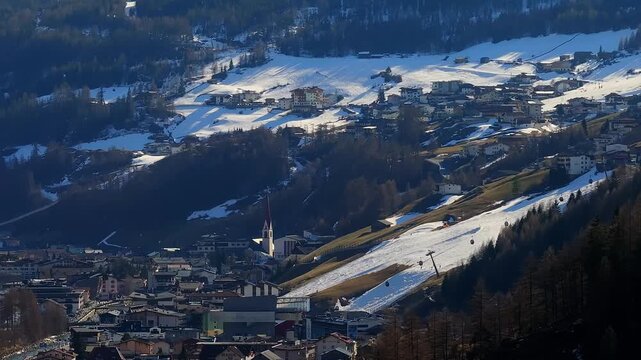 Aerial view of the alpine village featuring the church with a red spire and snow-covered ski slopes nestled in the mountains of Soelden, Tyrol, Austria.