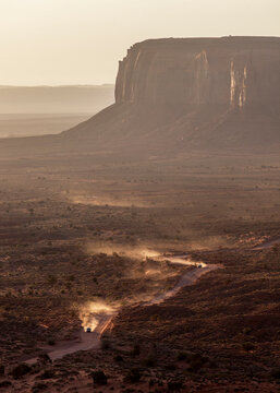 Off road vehicles driving through a dusty desert valley