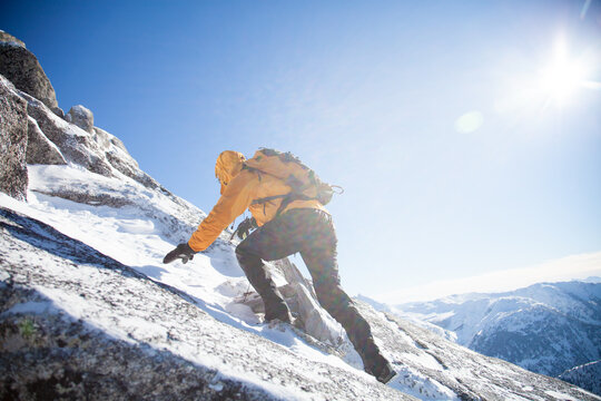 Mountaineer scrambling up a snowy mountain peak