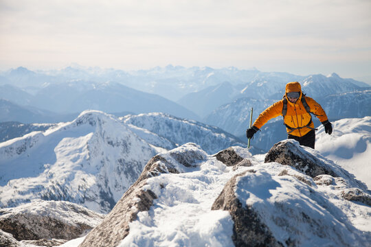 Man ascending a snowy mountain peak on a sunny day