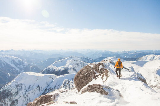 Hiker walks along snowy mountain ridge on sunny day