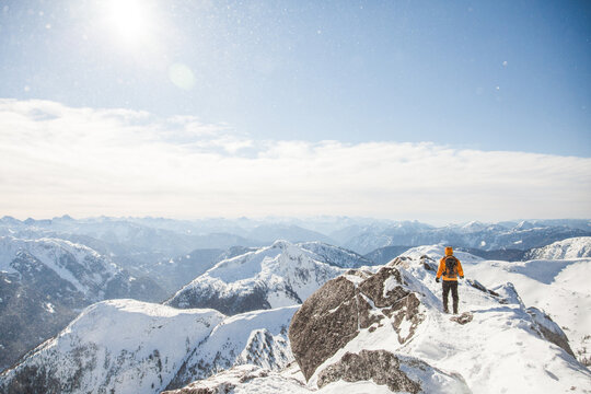 Hiker stands on snowy mountain summit overlook