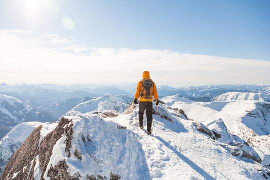 Mountaineer in a yellow jacket on a snowy peak