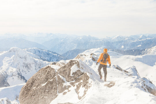 A hiker treks across a snowy mountain summit