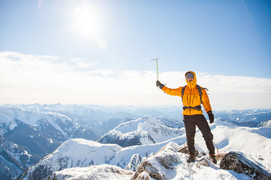Climber holding ice axe on mountain summit