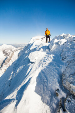 Male mountaineer on a windswept snowy mountain peak