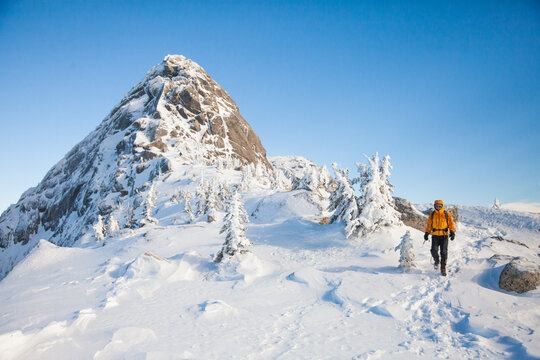 Man hikes through a snowy mountain landscape