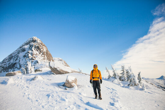 Hiker in yellow jacket on a snowy peak