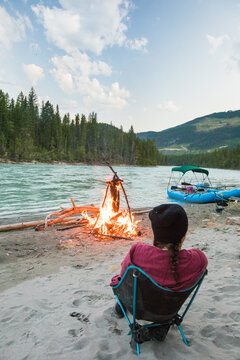 Person enjoying a campfire on a sandy riverbank