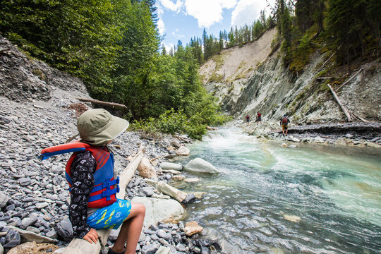 Young boy resting on a rocky river bank