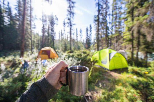 Enjoying morning coffee at a sunny forest campsite