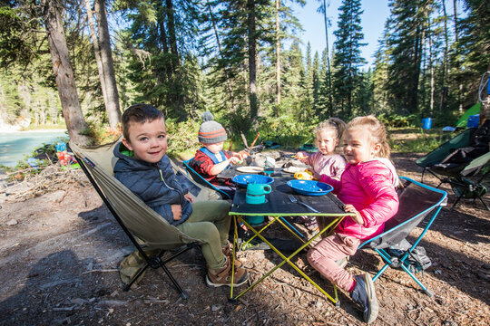 Young children enjoying a meal together at a forest campsite