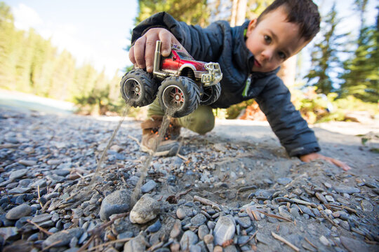 Young boy plays with a red toy monster truck