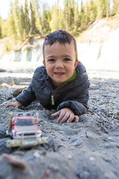 Young boy smiles while playing in the sand