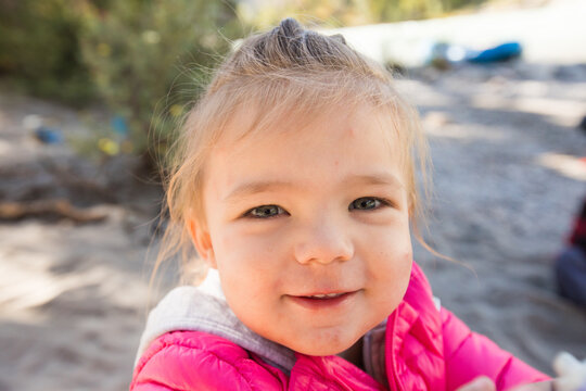 Happy toddler girl in pink jacket smiling outside