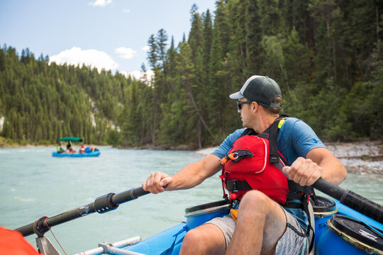 Man paddling an inflatable raft down a scenic river