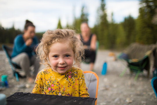 Cute little girl with curly hair smiles while camping