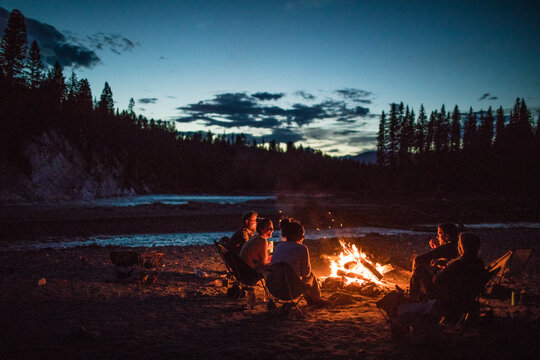 A group of friends around a campfire at dusk