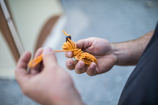 Man preparing an orange tent guy line