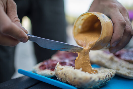 Person spreading creamy peanut butter on a roll
