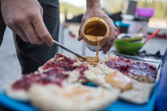 Man pouring peanut butter onto bread for sandwiches