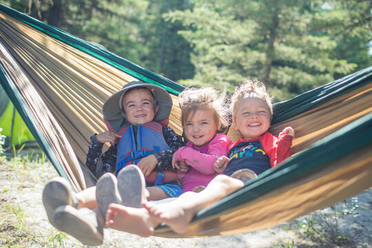 Three happy children laughing in a hammock outdoors