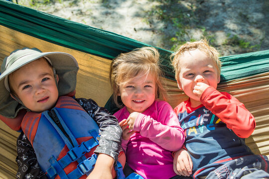 Three happy kids resting together in a hammock