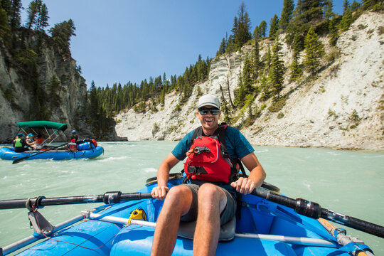 Smiling man rowing an inflatable river raft