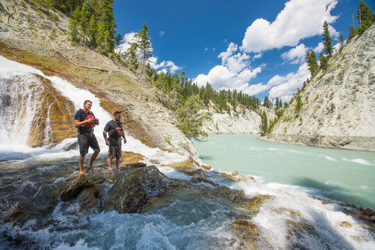 Two adventurous men explore a remote waterfall