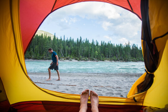 Point of view from tent of man walking on riverbank