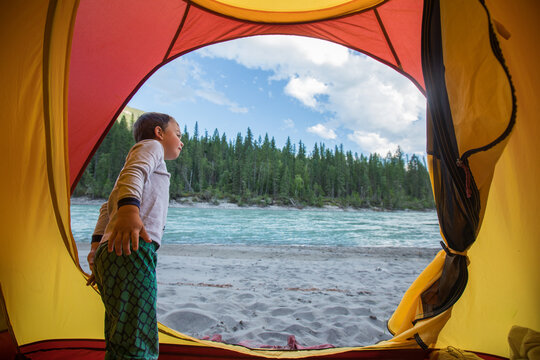 Curious boy camping by a river in the forest