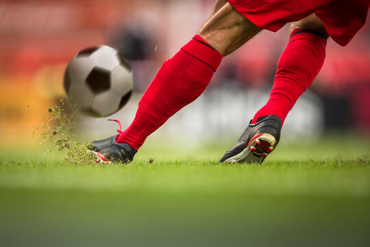 ction shot of a soccer player's feet kicking a ball on a grass field