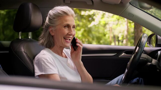 Positive smiling Caucasian old woman talking phone call inside car smile happy mature female talk mobile conversation friendly discuss communicating in auto senior retired grandma lady in automobile