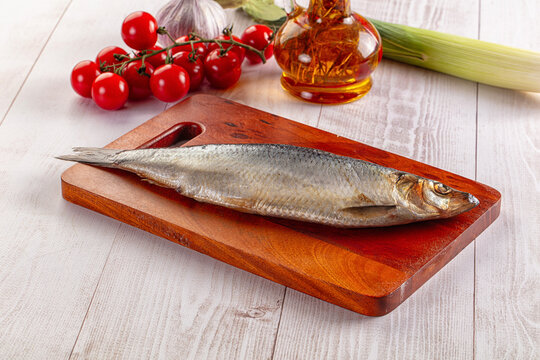 Smoked herring on wooden board with vegetables