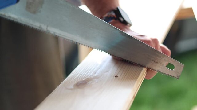 Discover the beauty of manual craftsmanship as a skilled carpenter uses a handsaw to cut through a wooden board. This video illustrates the dedication and technique required in this traditional craft.
