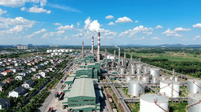 Aerial view of industrial factory complex with smokestacks and storage tanks near residential area