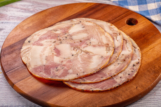 Sliced seasoned meat loaf on rustic wooden cutting board