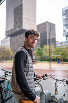 Young man standing with bicycle in urban setting