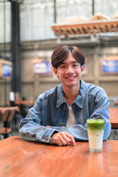 Smiling Asian man drinking iced matcha