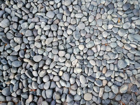 Smooth black and gray pebble stones background texture, natural decorative river rocks pattern for garden landscaping, zen spa or wallpaper design