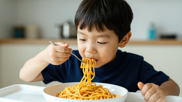 Boy Eating Spaghetti: A young boy eagerly enjoys a plate of spaghetti, twirling the noodles with a fork, embodying a moment of childhood delight and simple pleasure.