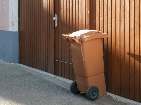 Brown Trash Bin Near Wooden Gate