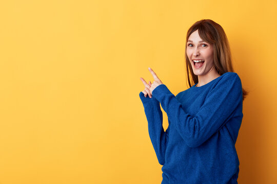 Smiling brunette in a blue sweater poses against a vibrant yellow backdrop, a bright studio portrait that conveys warmth, cheerfulness, and approachable casual style that resonates with lifestyle