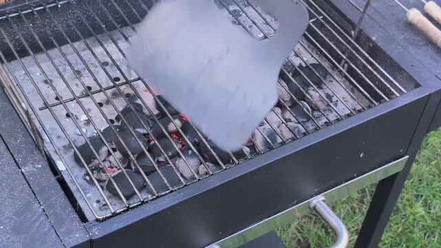 Starting a barbecue with charcoal briquette and preparing to grill in the backyard on a sunny day. Briquette coal is ignited