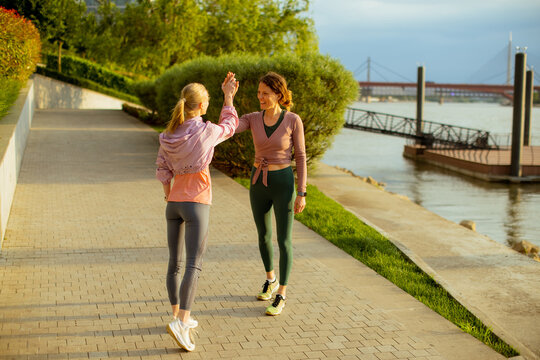 Friends share a joyful moment while walking by the river in the evening light