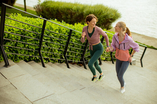 Friends run up steps next to a park near water in the morning