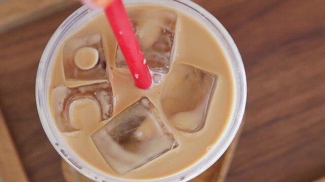 Refreshing iced coffee with cream swirls and ice cubes in a plastic cup