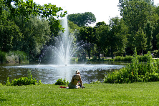 Giovane donna seduta sull'erba al parco cittadino di Amsterdam