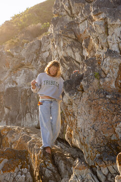 young woman climbing cliff rock, grotto beach, hermanus, South Africa