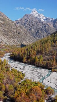 Aerial autumn view of Ecrins National Park in Hautes-Alpes, French Alps. Champoleon Valley with Drac Blanc River, forest and alpine mountain peak Sirac. France